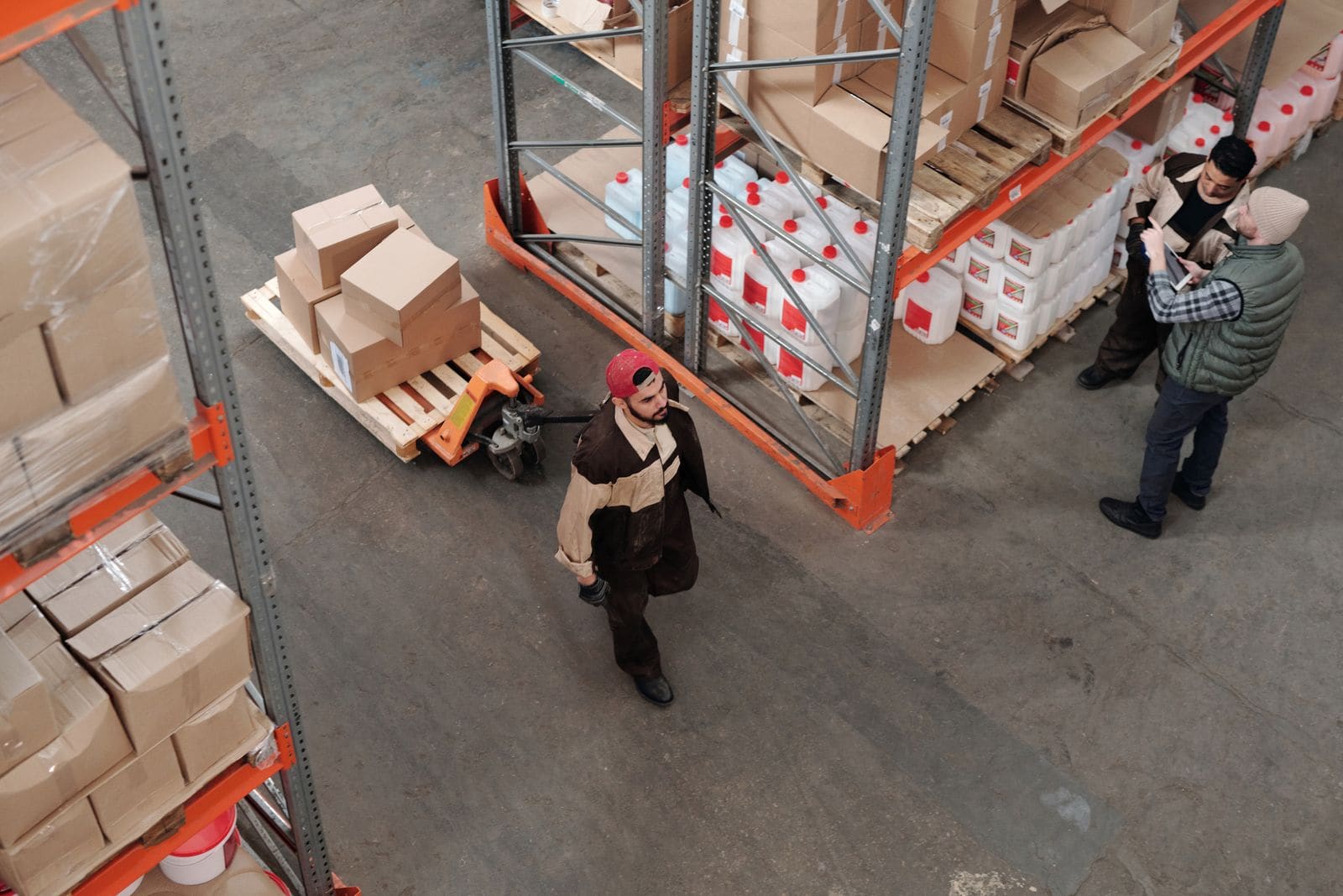 Warehouse racking aisles with pallet truck and staff